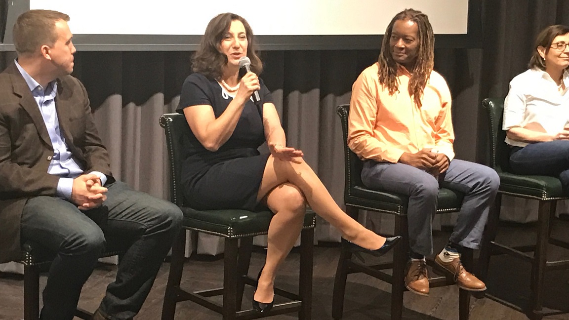 Four people speaking onstage during an event.